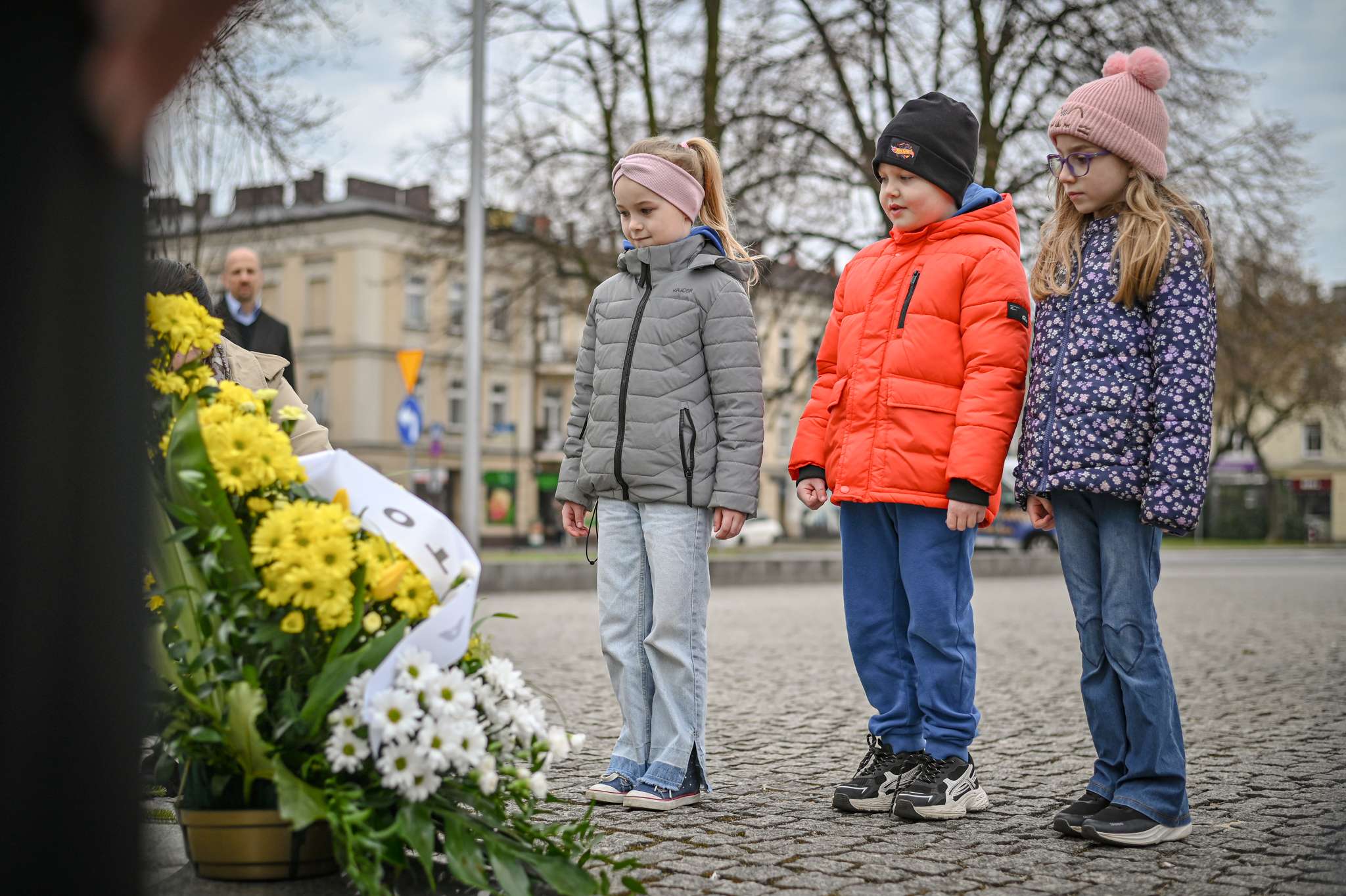 Kwiaty pod pomnikiem na Placu Daszyńskiego. W tle rocznica